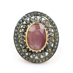 Peut inclure: Une bague en argent avec une grande pierre précieuse ovale rose entourée d'un délicat motif de filigrane serti de petits diamants.