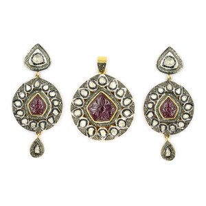 Può includere: Un set di orecchini d'oro e una collana con un ciondolo con una pietra preziosa di rubino circondata da diamanti. Gli orecchini e il ciondolo hanno un design circolare con un motivo floreale.