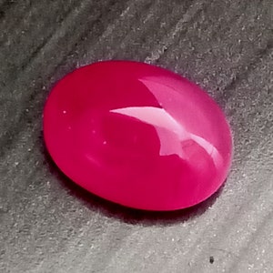Könnte beinhalten: Ein ovaler Edelstein in leuchtendem Pink mit einer glatten, polierten Oberfläche.