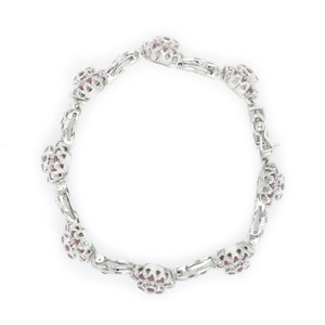 May include: A silver bracelet with a cluster of pink gemstones on each link.