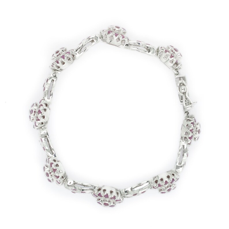 May include: A silver bracelet with a cluster of pink gemstones on each link.