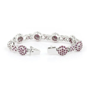 May include: A silver bracelet with a delicate chain design and round red ruby accents. The bracelet is open and ready to be worn.
