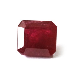 Puede incluir: Una piedra preciosa de color rojo intenso con un corte esmeralda rectangular.