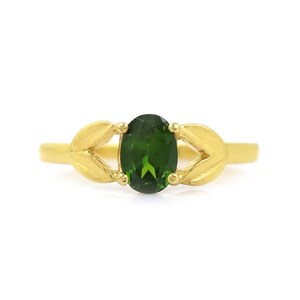 Può includere: Un anello d'oro con una pietra preziosa ovale verde incastonata in un design a foglia.