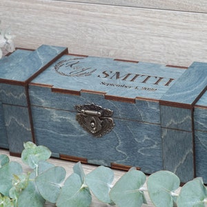 Pode incluir: Uma caixa de madeira azul com uma trava de metal e gravada com o texto "SMITH September 1, 2022".