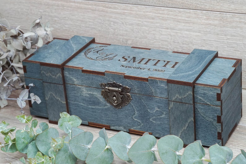 Pode incluir: Uma caixa de madeira azul com uma trava de metal e gravada com o texto "SMITH September 1, 2022".