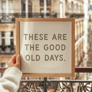May include: A wooden framed sign with a white background and the text "These are the good old days." in brown lettering.