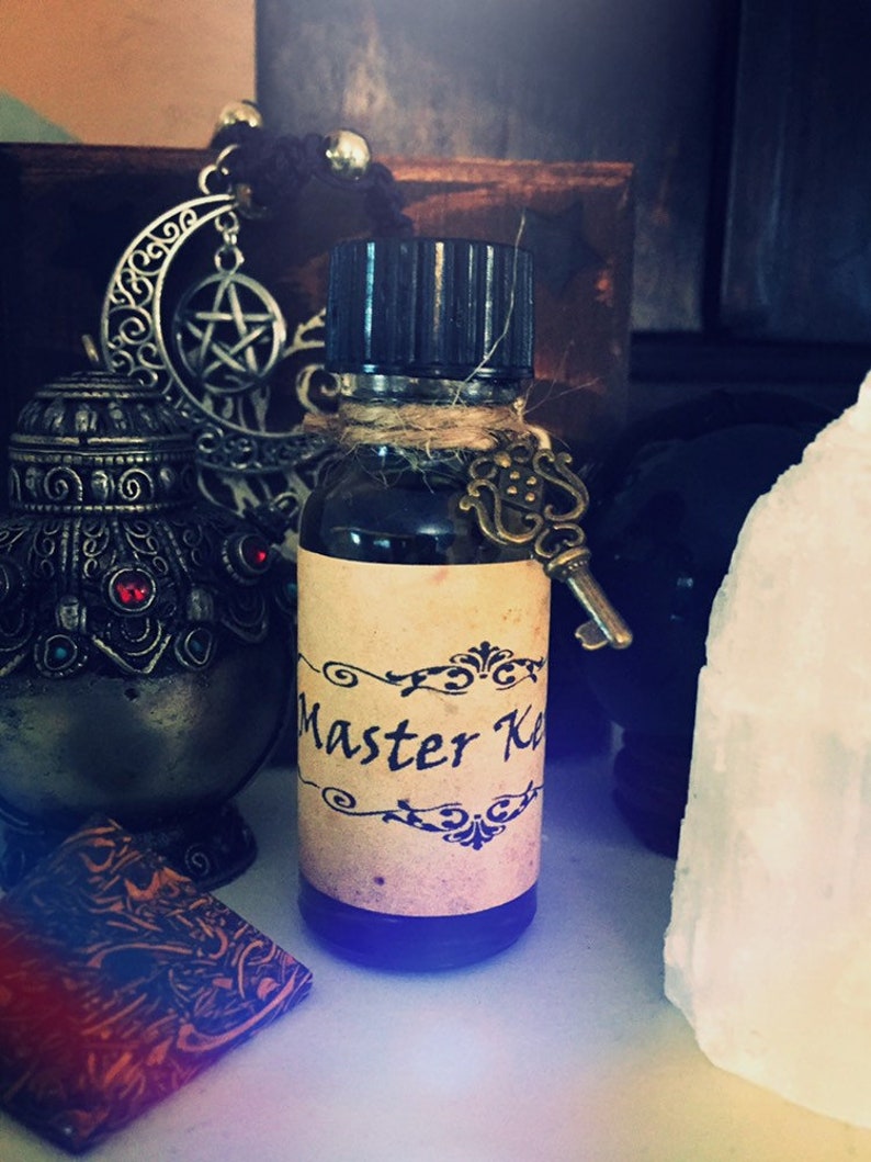 May include: A small glass bottle with a brown label that says "Master Key" and a key charm attached to the bottle. The bottle is sitting on a white surface.