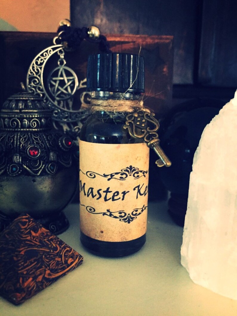 May include: A small brown glass bottle with a black cap and a label that says "Master Key". The bottle is tied with twine and has a small key charm attached.