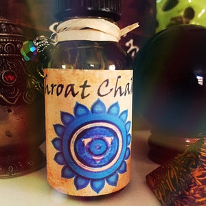May include: A small glass bottle with a black cap and a brown label. The label has a blue and white chakra symbol and the text "Throat Chakra".