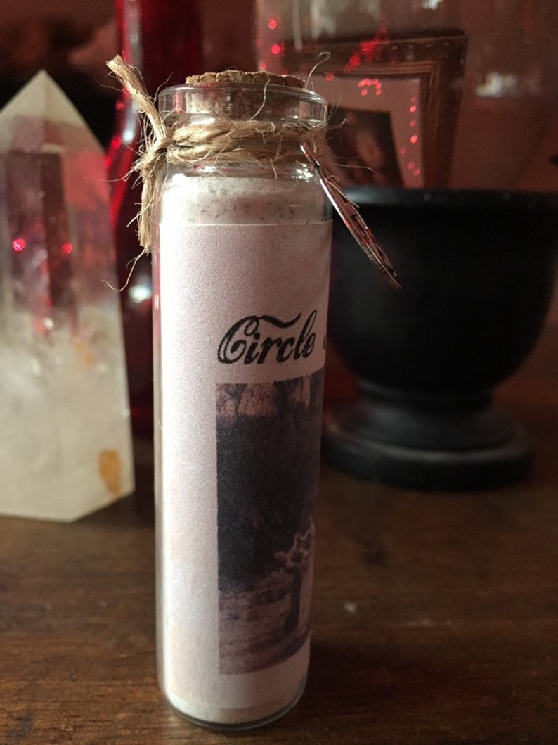 May include: A small glass bottle with a cork stopper and a twine closure. The bottle is filled with a white powder and has a label that says "Circle of".