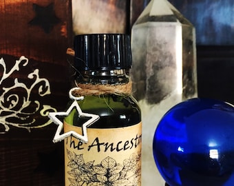 May include: A small, dark green glass bottle with a black cap and a silver star charm. The bottle is labeled "The Ancestor" and "Ravens Moon".