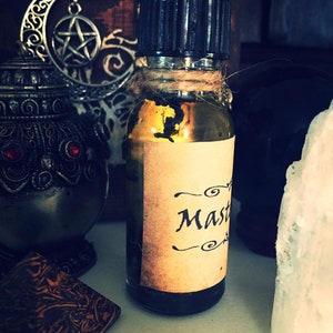 May include: A small glass bottle with a black cap and a brown paper label that says "Master" in a cursive font. The bottle is filled with a dark liquid and is sitting on a white surface.