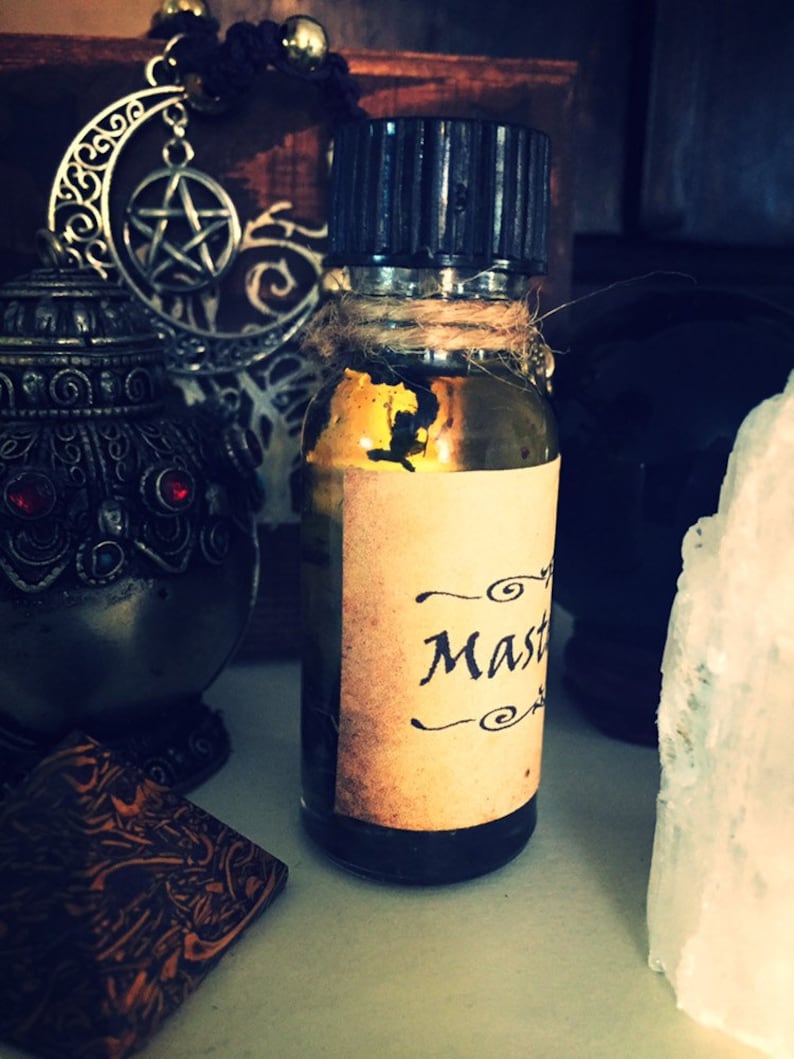 May include: A small glass bottle with a black cap and a brown paper label that says "Master" in a cursive font. The bottle is filled with a dark liquid and is sitting on a white surface.