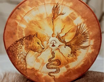 May include: A round, leather-bound drum with a painted design. The design features a leopard, a snake, an eagle, and a bird. The background is a light brown color with a sunburst pattern.