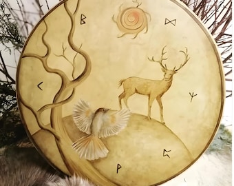 May include: A round, tan-colored drum with a painted design. The design features a tree, a bird in flight, a deer, and a sun. There are also several runes painted around the edge of the drum.