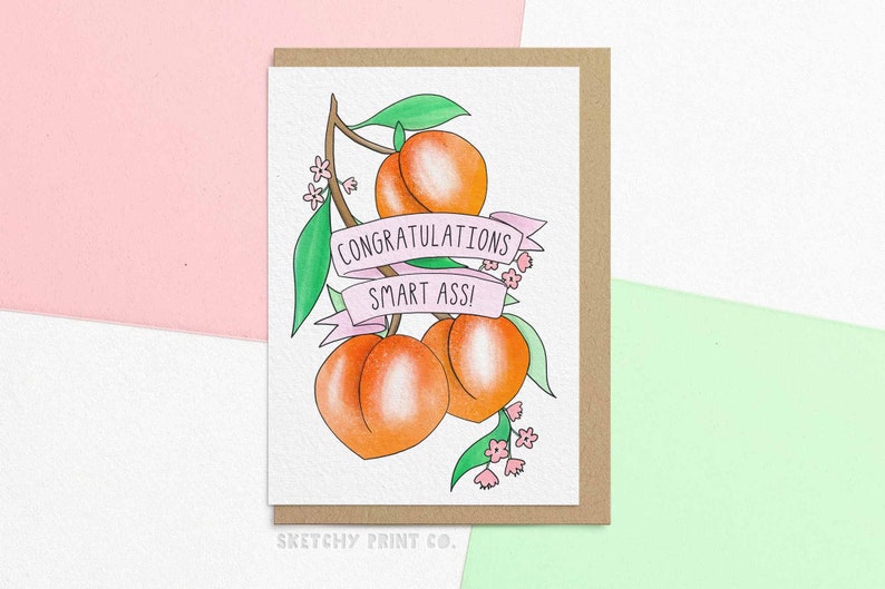 May include: A greeting card with a peach illustration and the text "Congratulations Smart Ass!" in pink lettering.