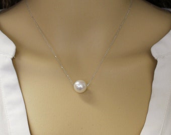 Puede incluir: Un collar de cadena de plata simple con un solo colgante de perla blanca grande.