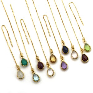 May include: A set of ten gold chain earrings with teardrop-shaped gemstones. The gemstones are in various colours, including green, blue, purple, pink, and clear.