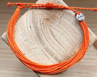 May include: Orange braided bracelet with a silver charm that says "Karma".