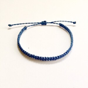 Könnte beinhalten: Ein schlichtes blaues Freundschaftsarmband aus geflochtener Schnur. Das Armband ist verstellbar und kann an jede Handgelenksgröße angepasst werden.