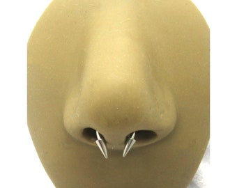 May include: A close-up of a nose piercing with two silver spikes. The piercing is 8mm in size.