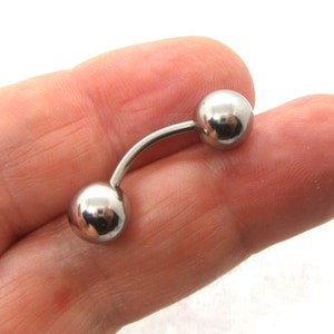 May include: A silver curved barbell with two round balls on each end.