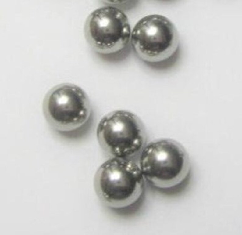 May include: A group of silver-colored metal balls. The balls are smooth and round.