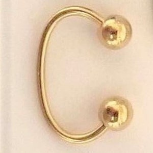 May include: Gold-toned hoop earring with two round balls at the ends.