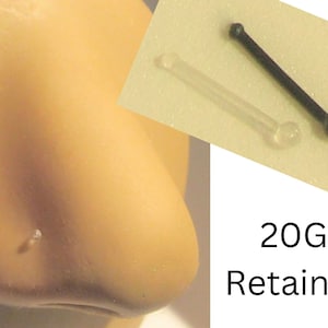 May include: A close-up of a clear nose ring retainer with a small ball on the end. The retainer is 20 gauge and is shown next to a black nose ring retainer with a ball on the end. The text "20G Retainer" is visible below the image.