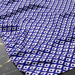 May include: A blue and white patterned fabric with a repeating geometric design. The fabric is draped, showing the texture and flow of the material. The design features a series of eye-like shapes in a repeating pattern. The logo "DEVARSHY PRINTS" is visible.