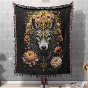 May include: A black woven throw blanket with a gold and blue wolf illustration surrounded by flowers. The wolf has a detailed design with gold accents and a floral pattern. The text "Devarshy Home" is in the top right corner of the blanket.