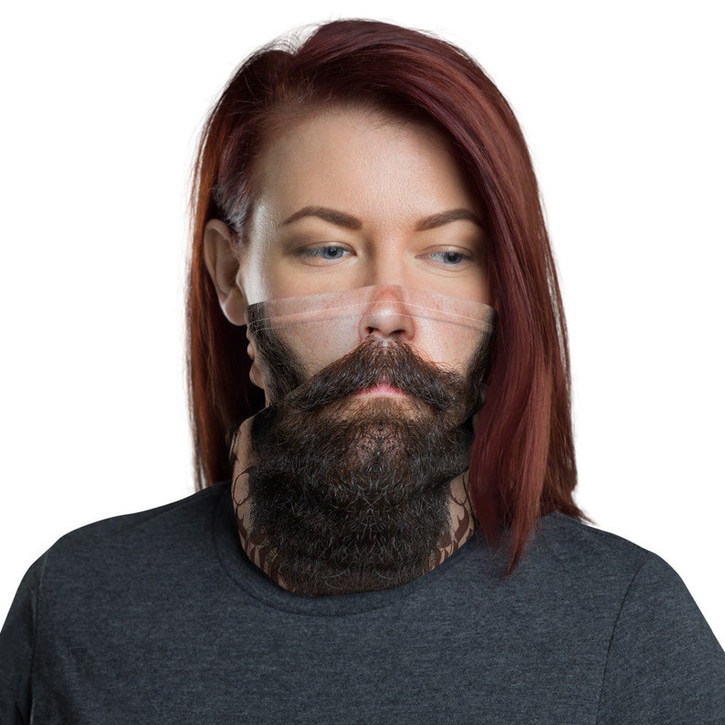 May include: A woman with long red hair is wearing a black neck gaiter with a printed image of a man's face with a beard and mustache.
