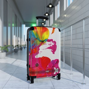 Abstract art hard shell suitcase featuring vibrant splashes of pink, red, yellow, orange, and blue on a glossy white background. Modern spinner luggage for creative travelers, perfect as a gift for artists and color lovers. Stylish carry-on suitcase with bold, unique painting-inspired design, ideal for holidays, business trips, and fashion-forward journeys. Durable, lightweight case blends contemporary aesthetics with bright pop art energy for men and women.