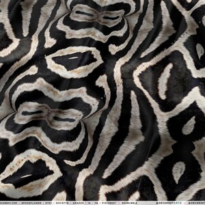 May include: Close-up of a fabric with a black and white zebra stripe pattern. The design features bold, irregular stripes, creating a striking visual texture. The fabric appears to have a soft, slightly textured surface.