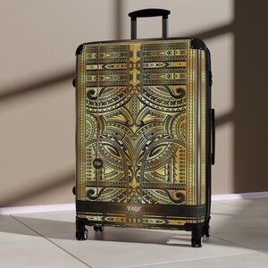 May include: A gold and black rolling suitcase with an intricate tribal pattern. The suitcase has a telescoping handle and four wheels. The text "DEWARSHY" is printed on the bottom of the suitcase.