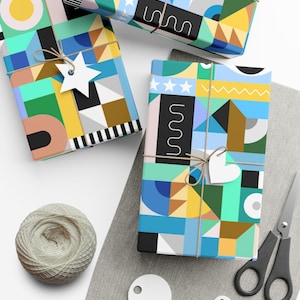 Puede incluir: Tres cajas de regalo envueltas en papel con estampado geométrico de colores. El papel presenta una variedad de formas, incluyendo círculos, cuadrados, triángulos y estrellas. Las cajas están atadas con cuerda y decoradas con estrellas y corazones de papel blanco.