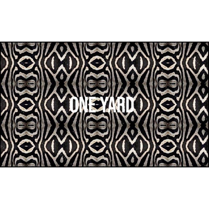 May include: A rectangular fabric with a black and white zebra stripe pattern. The text "ONE YARD" is centered in white. The design features a symmetrical arrangement of the zebra print.