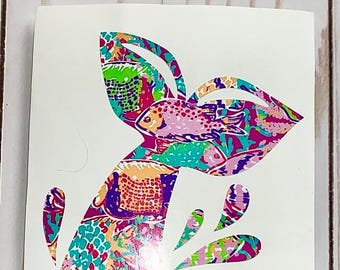May include: A colorful vinyl decal of a mermaid tail with a floral and fish pattern. The tail is pink, purple, green, and blue.