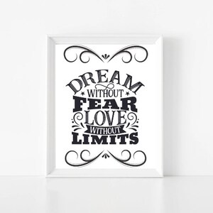 Puede incluir: Impresión tipográfica en blanco y negro con el texto "Dream without fear, love without limits" enmarcada en un marco blanco.