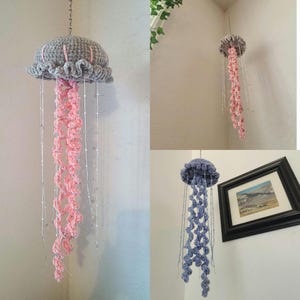 May include: Three crocheted jellyfish hanging from the ceiling. The jellyfish are gray, pink, and blue. They are made with yarn and have beaded tails.