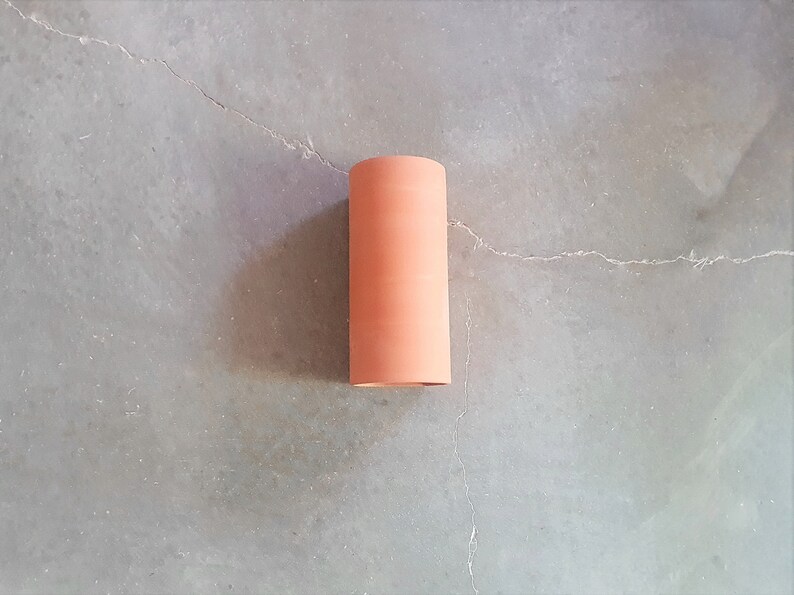 May include: A rolled up piece of terracotta-colored material on a gray concrete surface.