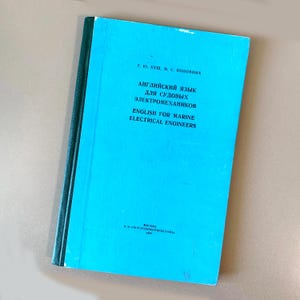 May include: A blue book titled "English for Marine Electrical Engineers" in English and Russian. The book has a light blue cover with black text and a dark green spine. The book is slightly angled.