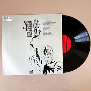 Puede incluir: Un álbum de vinilo vintage de Bertolt Brecht, titulado "Songs Gedichte Prosa Hanns Ernst Jäger" en texto negro sobre fondo blanco. La portada presenta una ilustración en blanco y negro de un hombre. Se ve un disco de vinilo negro.
