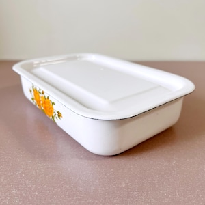 Puede incluir: Plato para hornear de esmalte blanco con tapa y un diseño floral con flores amarillas y hojas verdes.