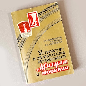 Puede incluir: Libro vintage con una cubierta de color beige, con logotipos rojos y blancos y texto cirílico. El título incluye "Жигули" y "Москвич". La cubierta tiene un borde decorativo y muestra signos de desgaste.