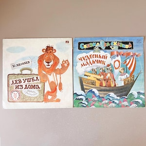 Puede incluir: Dos portadas de discos de vinilo vintage. Una presenta un león sonriente con una maleta, el texto "Lev Ushel Iz Doma" y el nombre "Yu. Yakovlev". La otra representa un barco con marineros y el texto "Skazka Za Skazkoy".