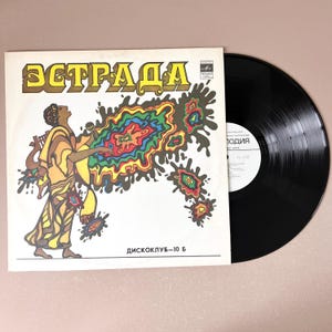 Puede incluir: Un disco de vinilo vintage con un diseño abstracto colorido en la portada. La portada presenta a una mujer sosteniendo un micrófono y un instrumento musical. El título del disco es "ЭСТРАДА" y la etiqueta es "ДИСКОКЛУБ-10 Б".