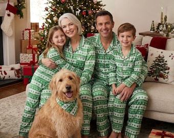 Op de afbeelding: Een gezin van vier personen draagt bijpassende groen-witte pyjamasets met lange mouwen, knoopsluiting en kraag, voorzien van een herhalende kerstprint. Een goudkleurige hond zit op de voorgrond en draagt een bijpassende groen-witte bandana om de nek.