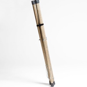 Puede incluir: Un conjunto de tres patas de tr&iacute;pode de madera con puntas de goma negras y una cadena plateada que las conecta. Las patas est&aacute;n plegadas juntas y est&aacute;n listas para ser utilizadas como un soporte.